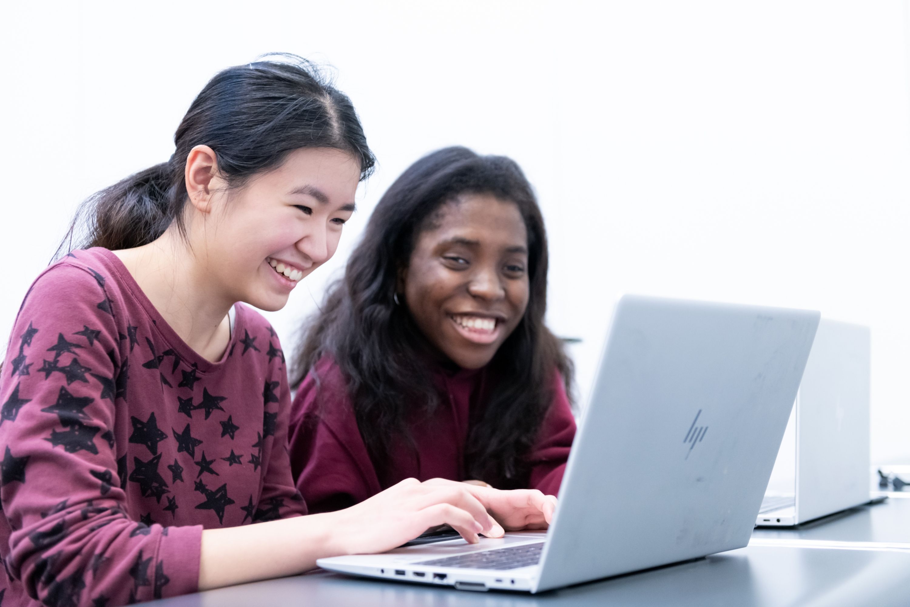 Two students smiling at a laptop