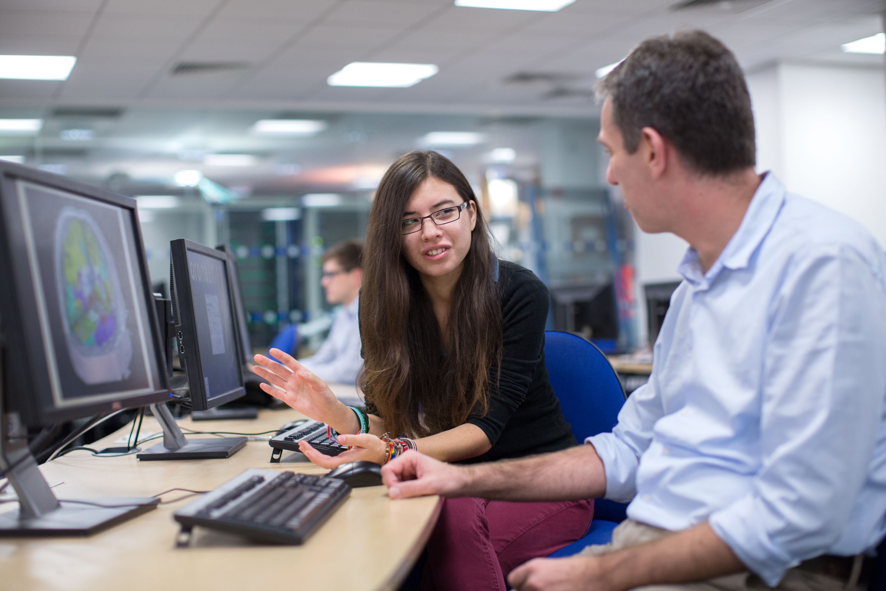 Professor and student discussing project in front of computers