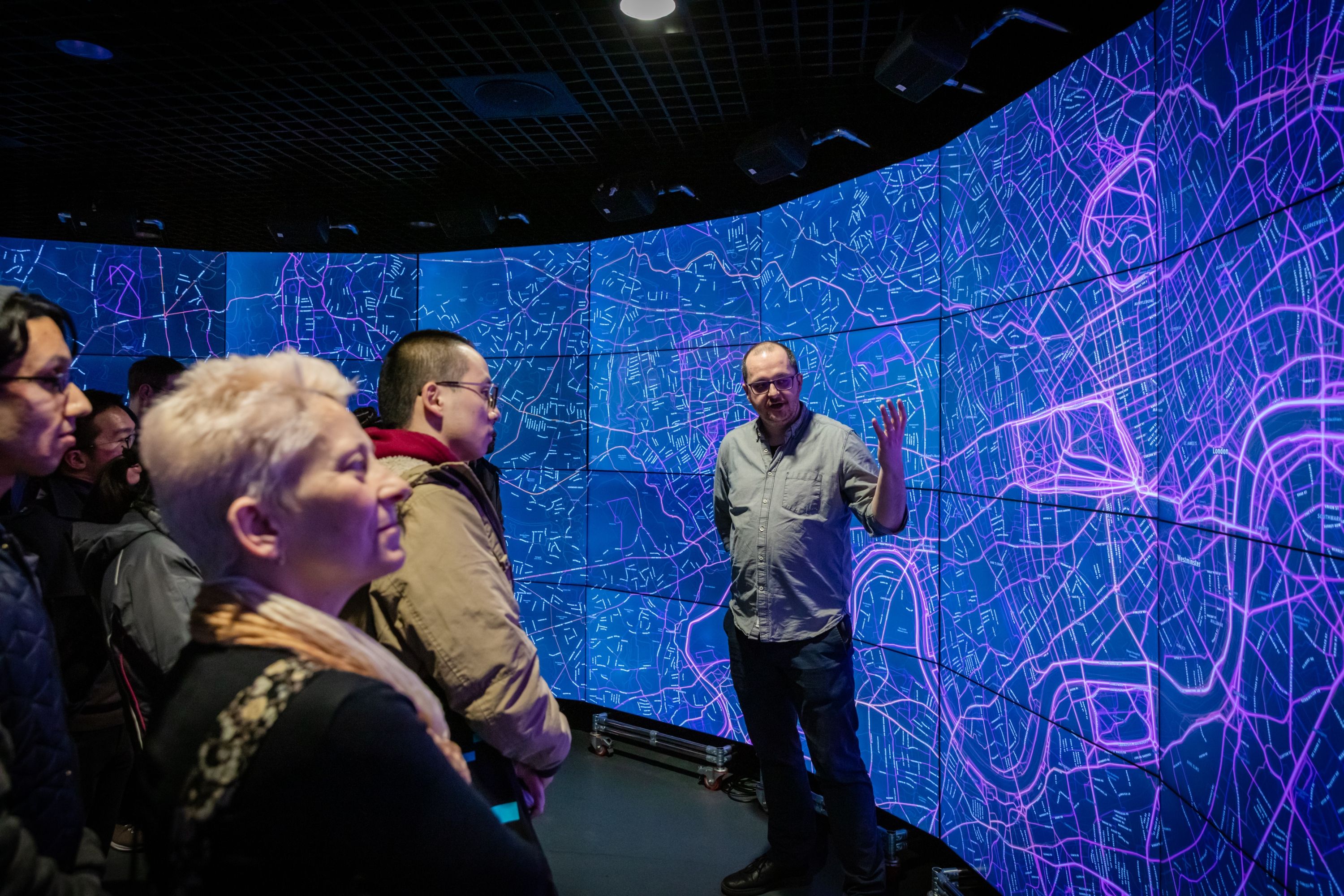 Person speaks in front of large screen to audience