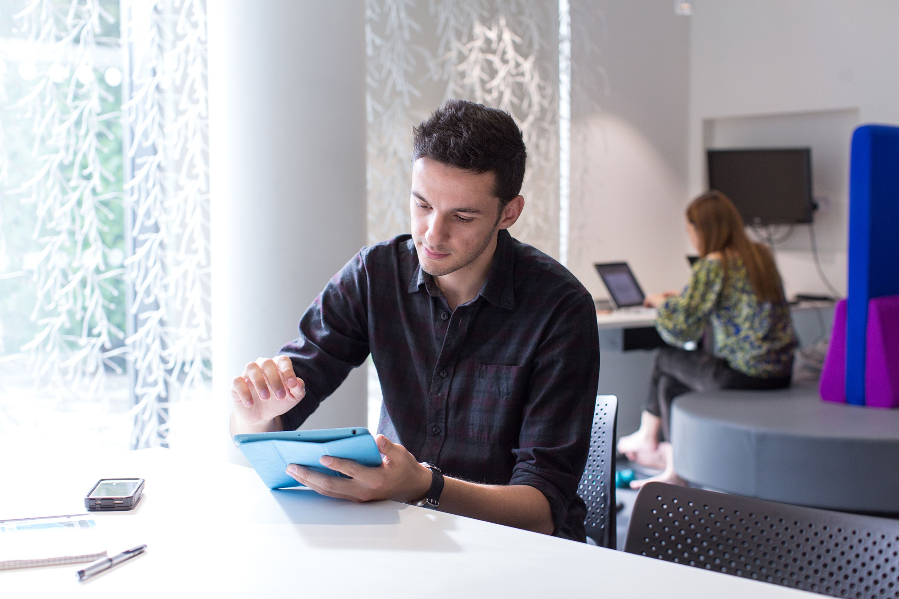 A student holding a blue tablet device in student accommodation