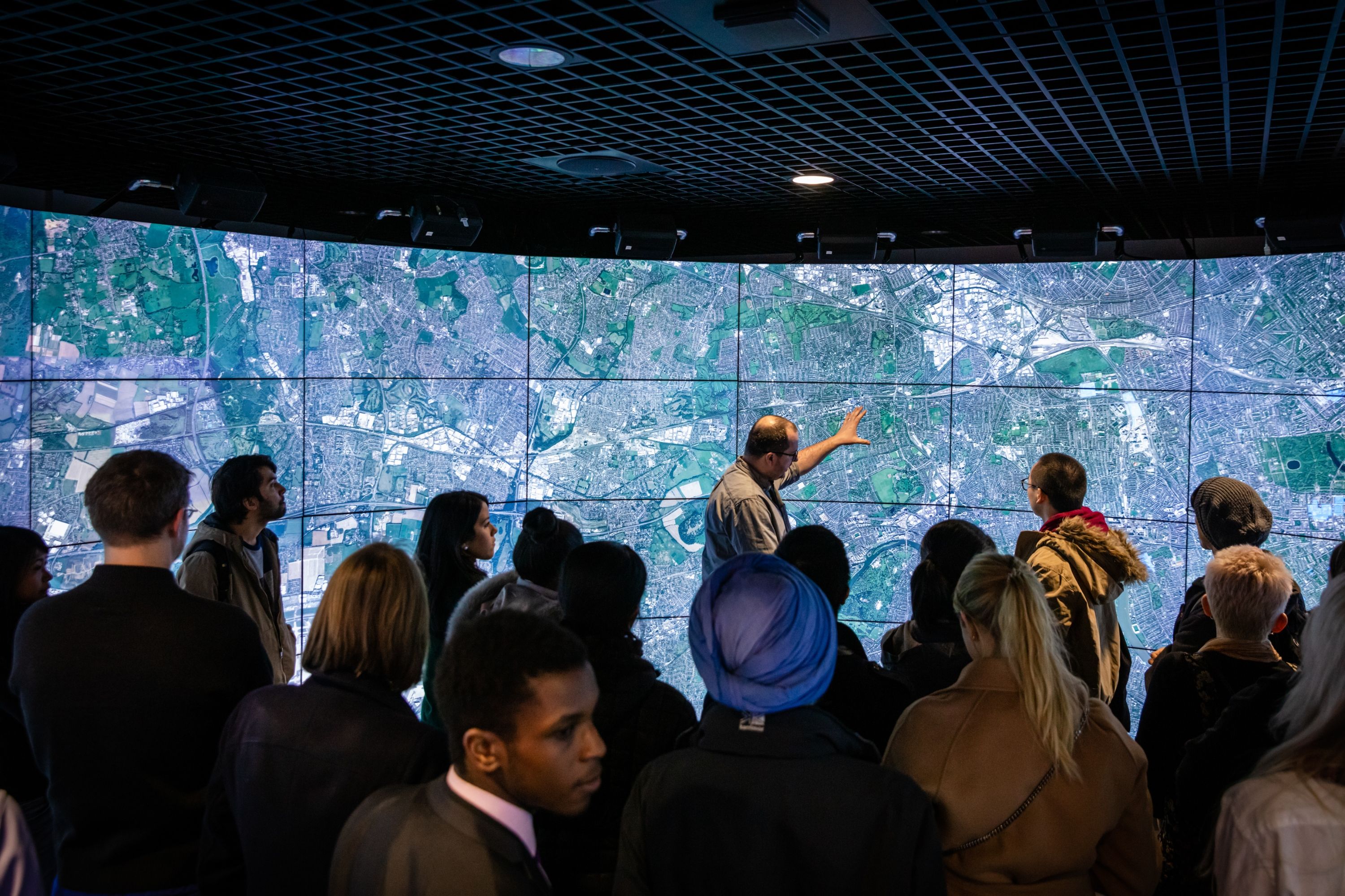 Person speaks in front of large screen to audience