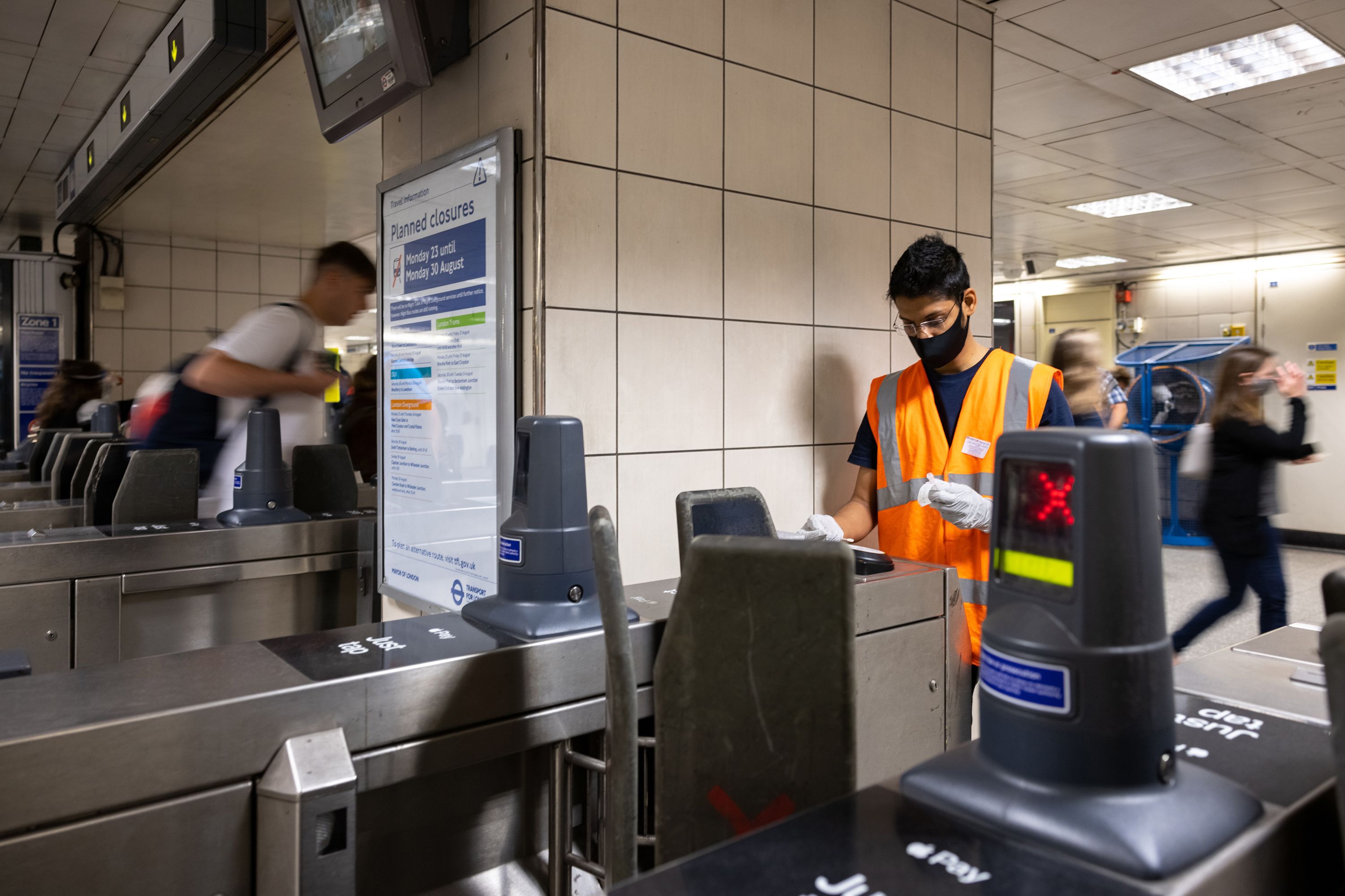 A student swabbing an entry barrier in a tube station