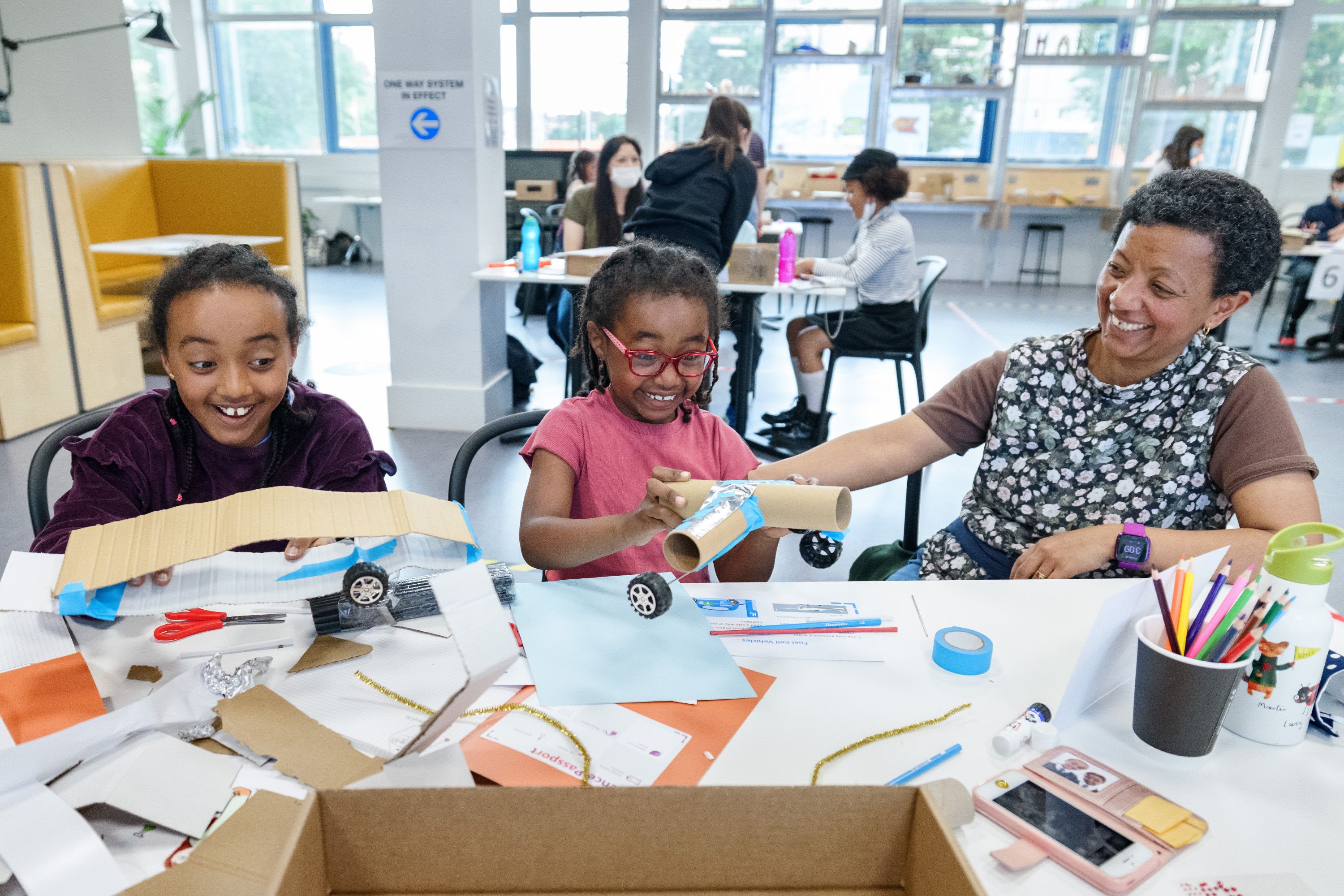 A woman and two children smiling as they play with craft supplies