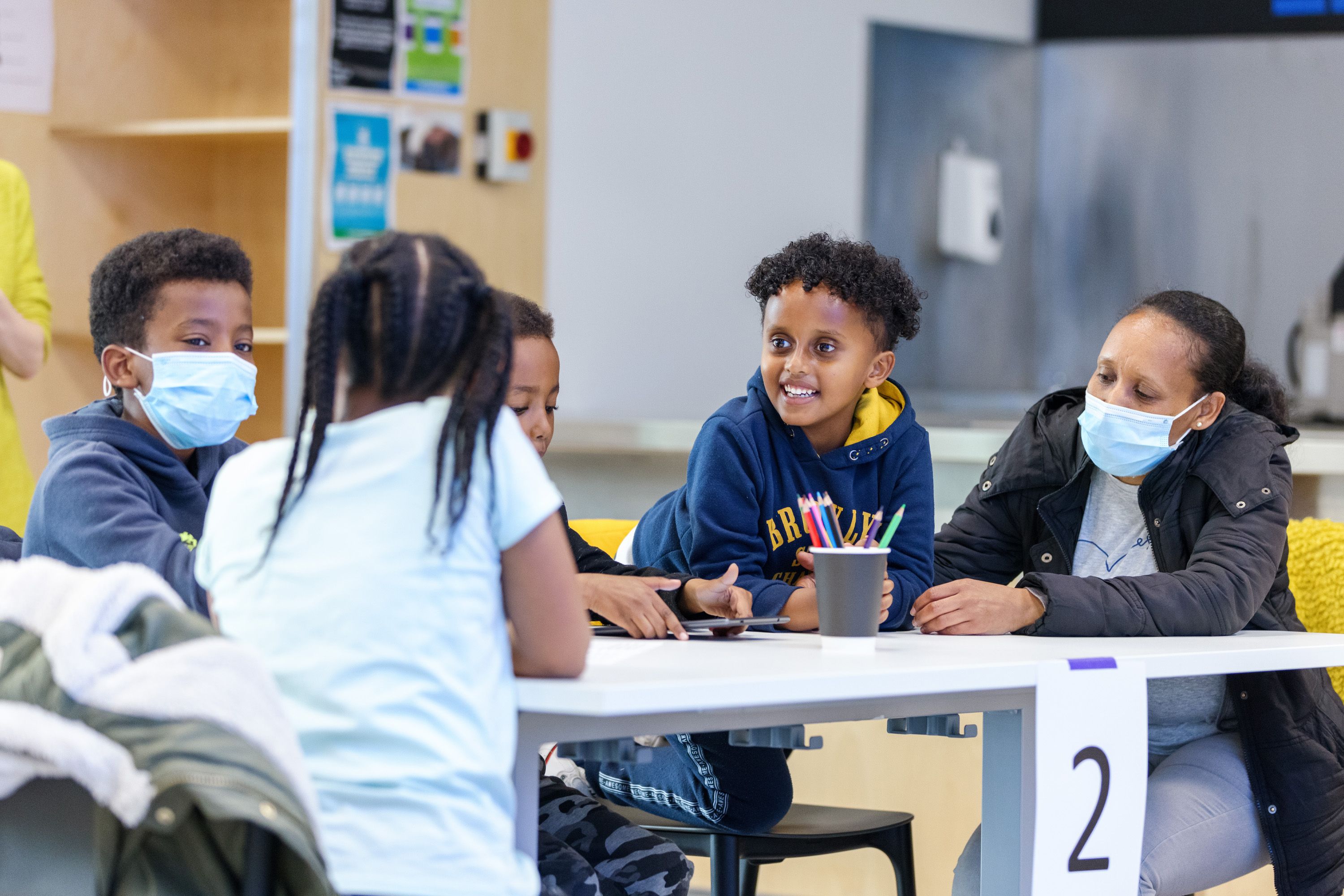 A group of smiling children sitting around a table with pens and pencils on it