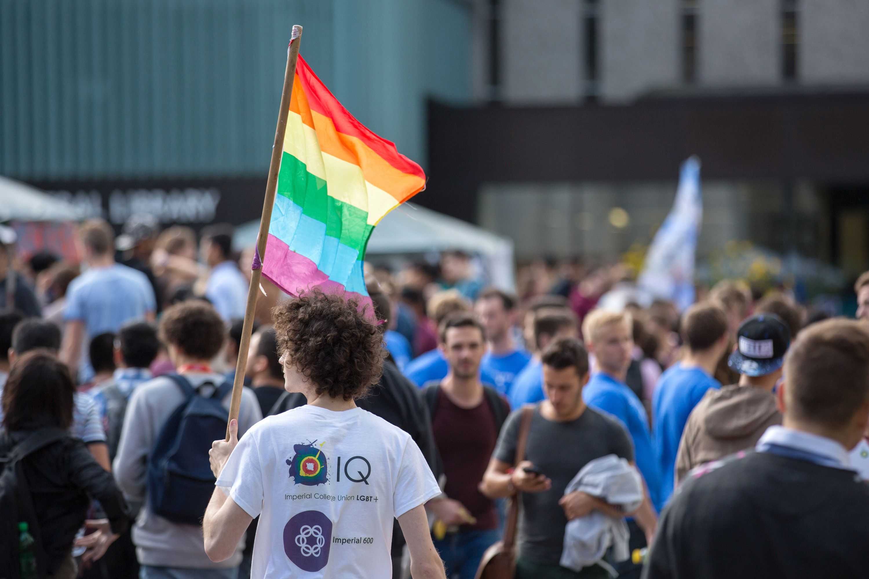 Crowd of people with a Pride multi-coloured flat in the centre