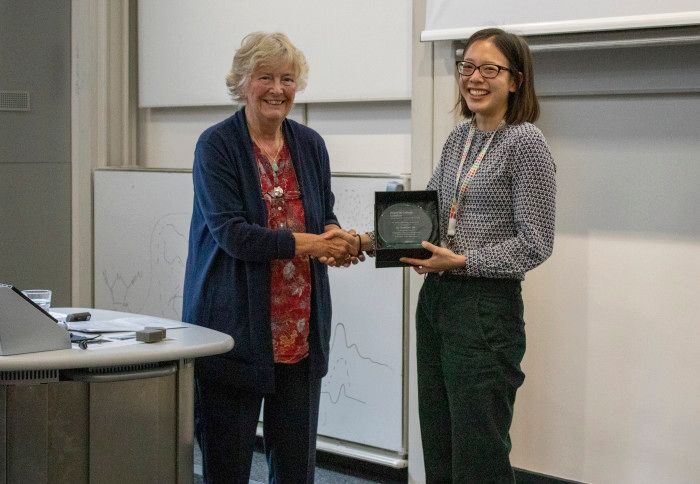 One woman handing another woman a trophy and shaking her hand