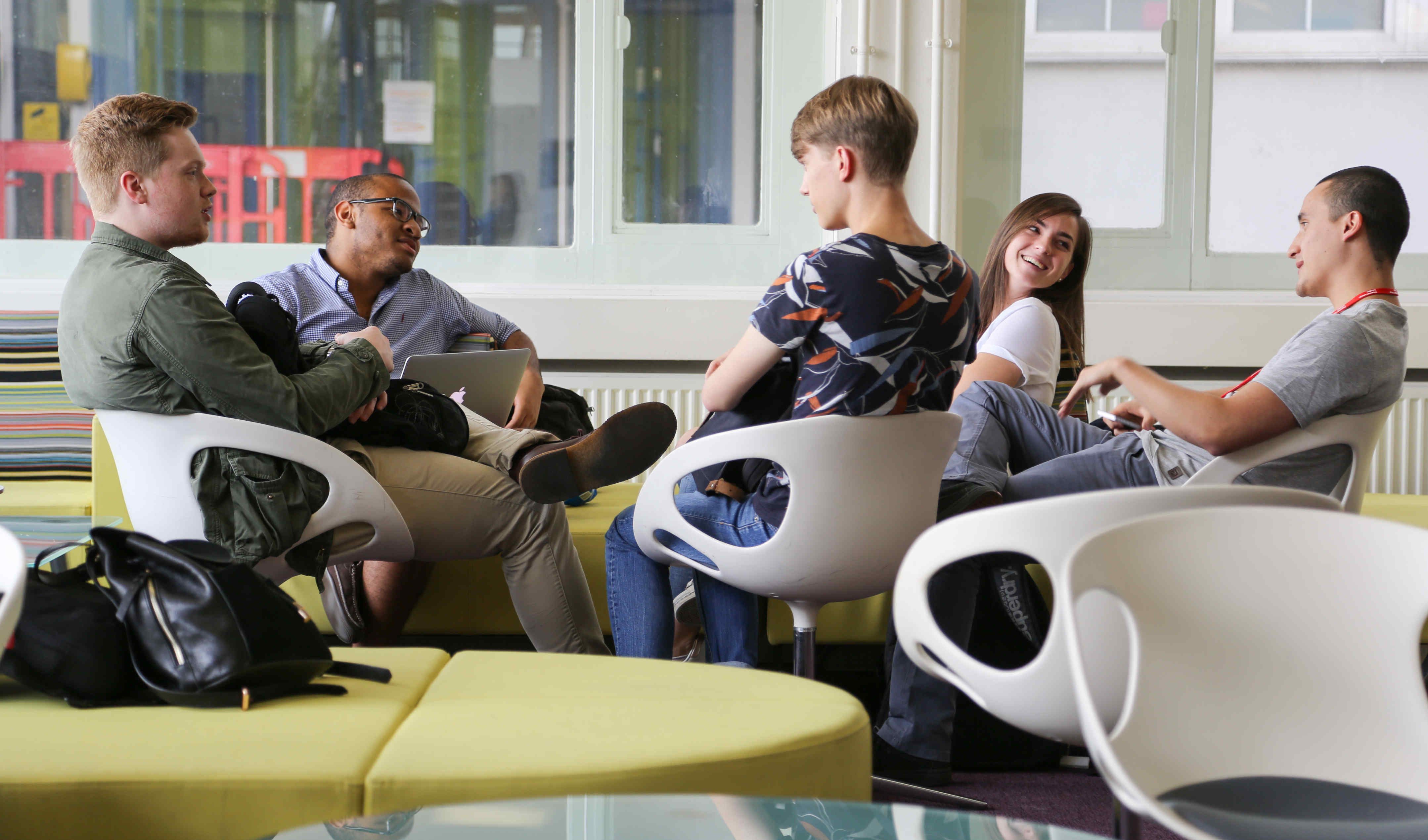 Five summer school students sitting down engaging in a discussion 