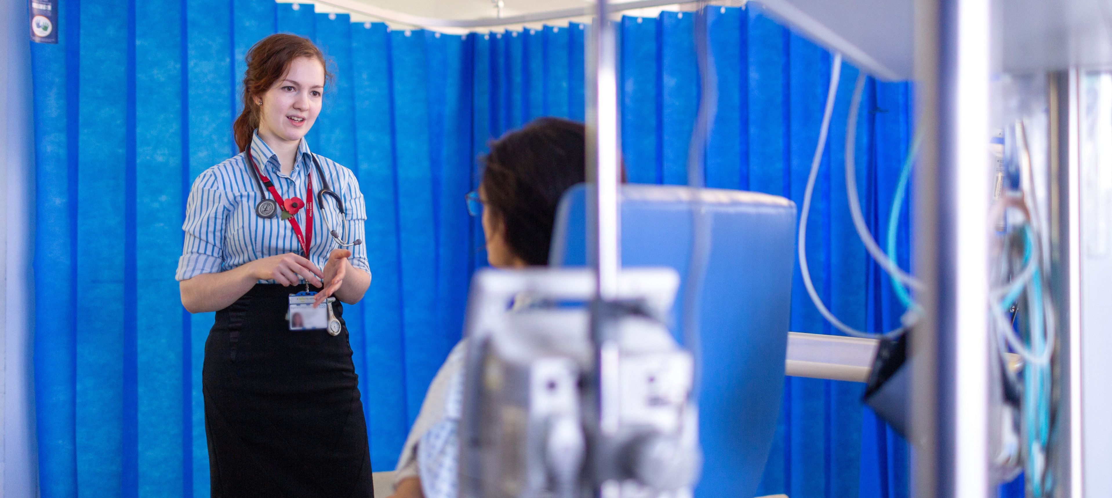 Student speaking to patient in hospital cubical 