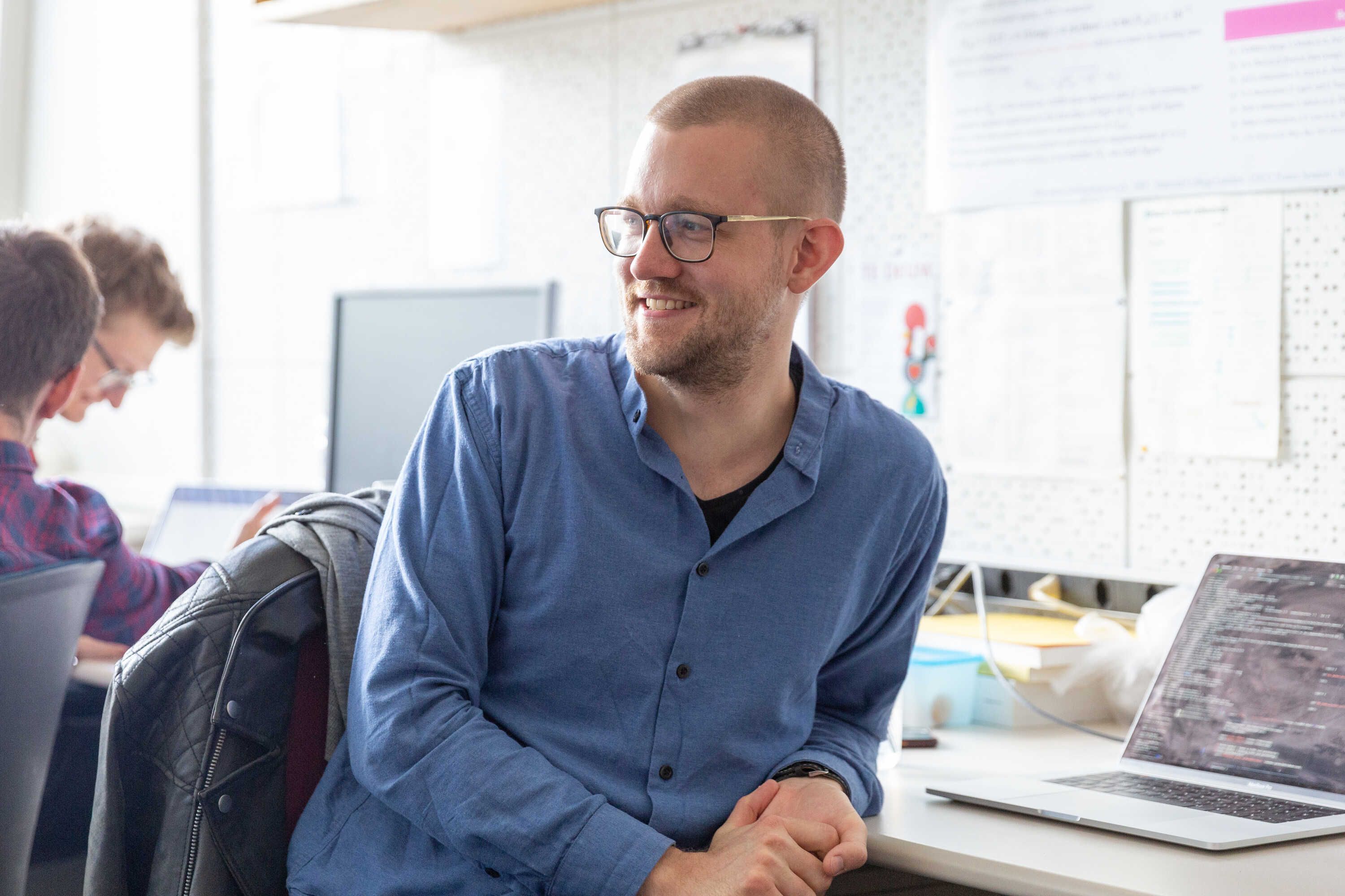 Researcher at CERN sitting in chair smiling