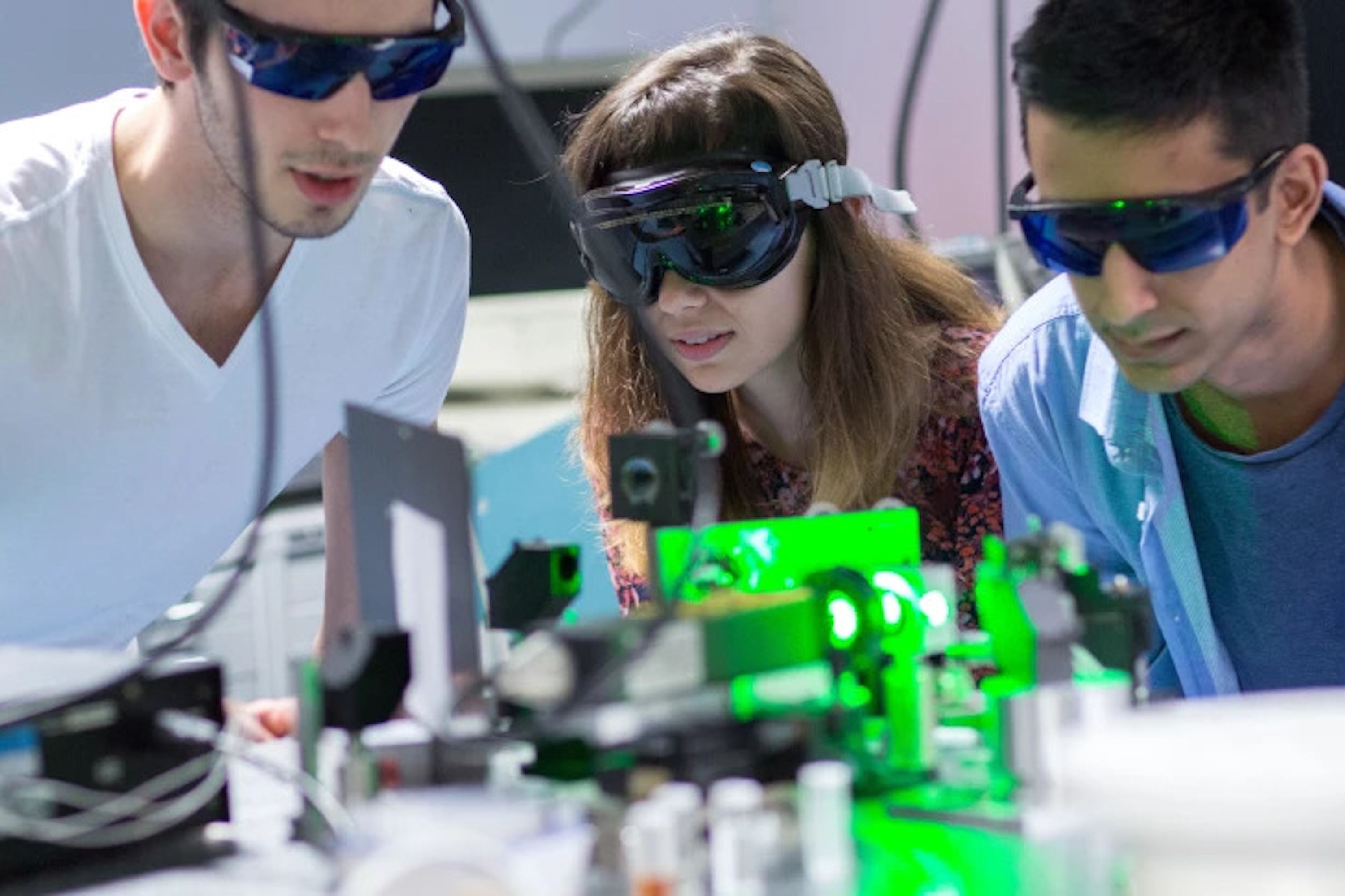 Students in safety goggles working with laser equipment