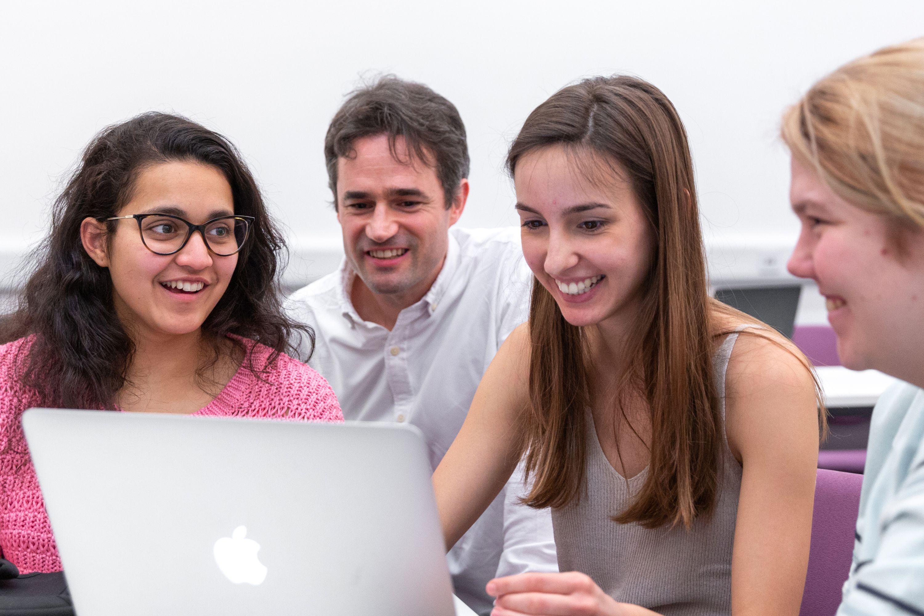 Four people sat around a laptop smiling