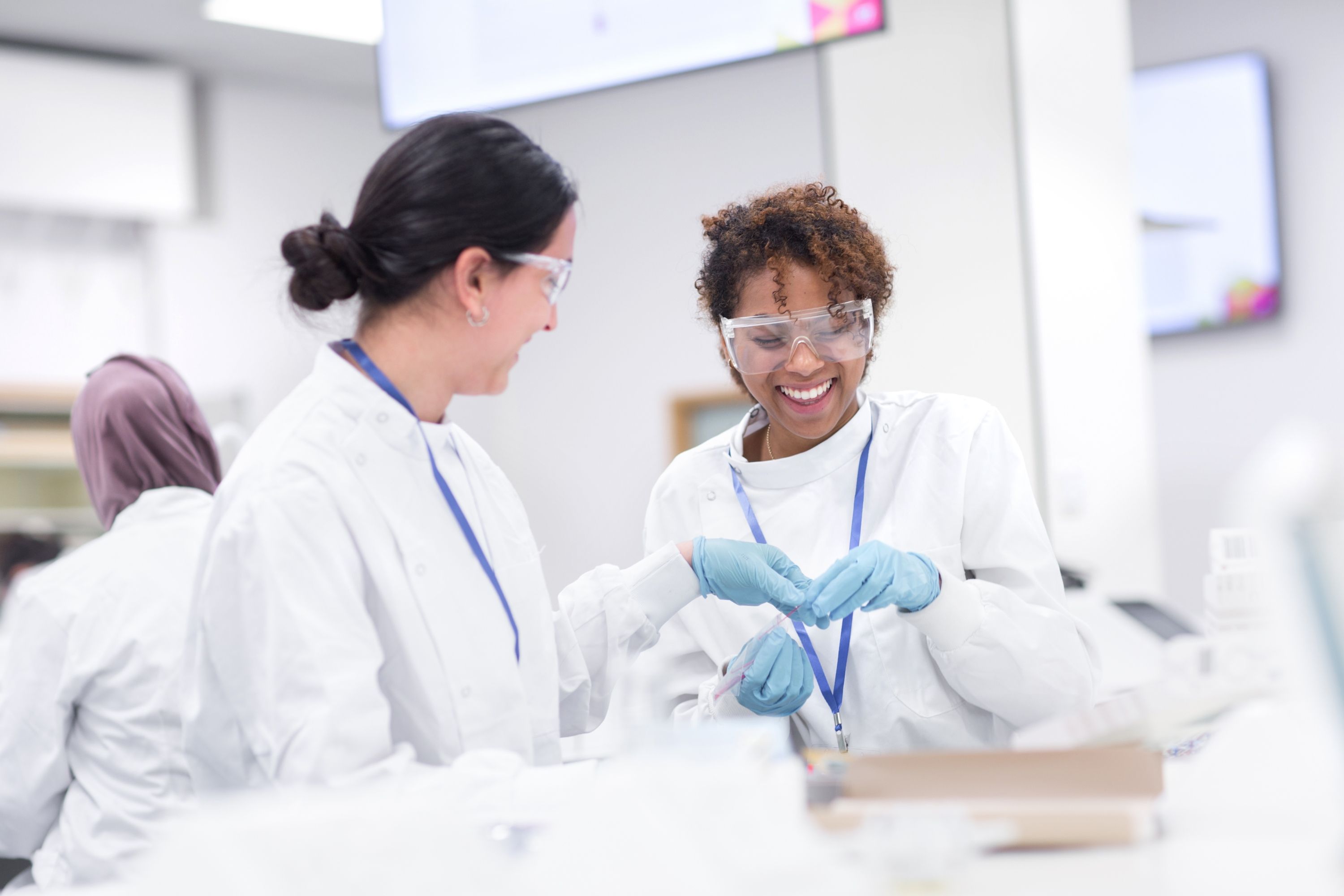 Two students in lab coats smiling