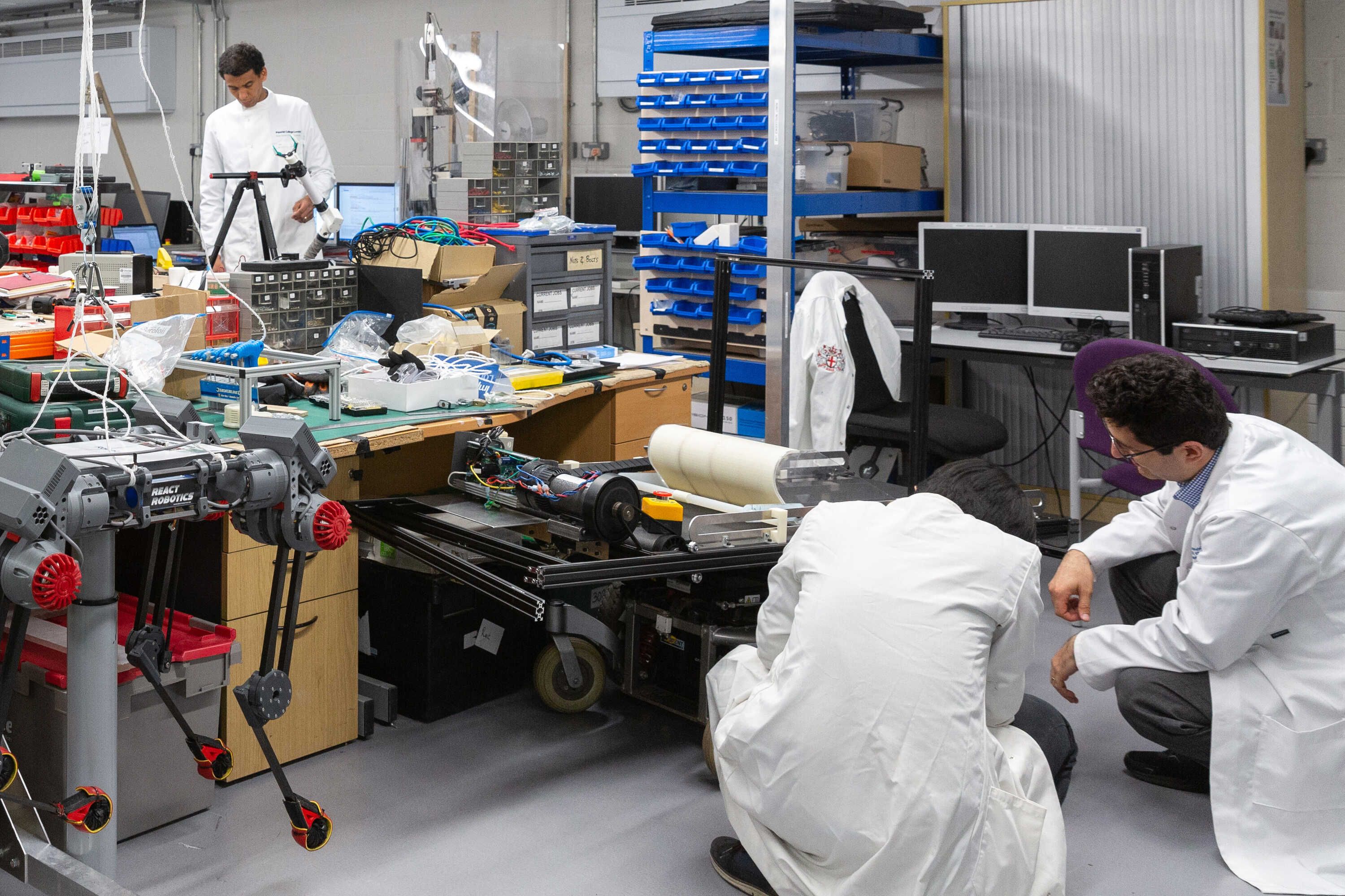 A group of students in a lab wearing white overcoats and working at machines