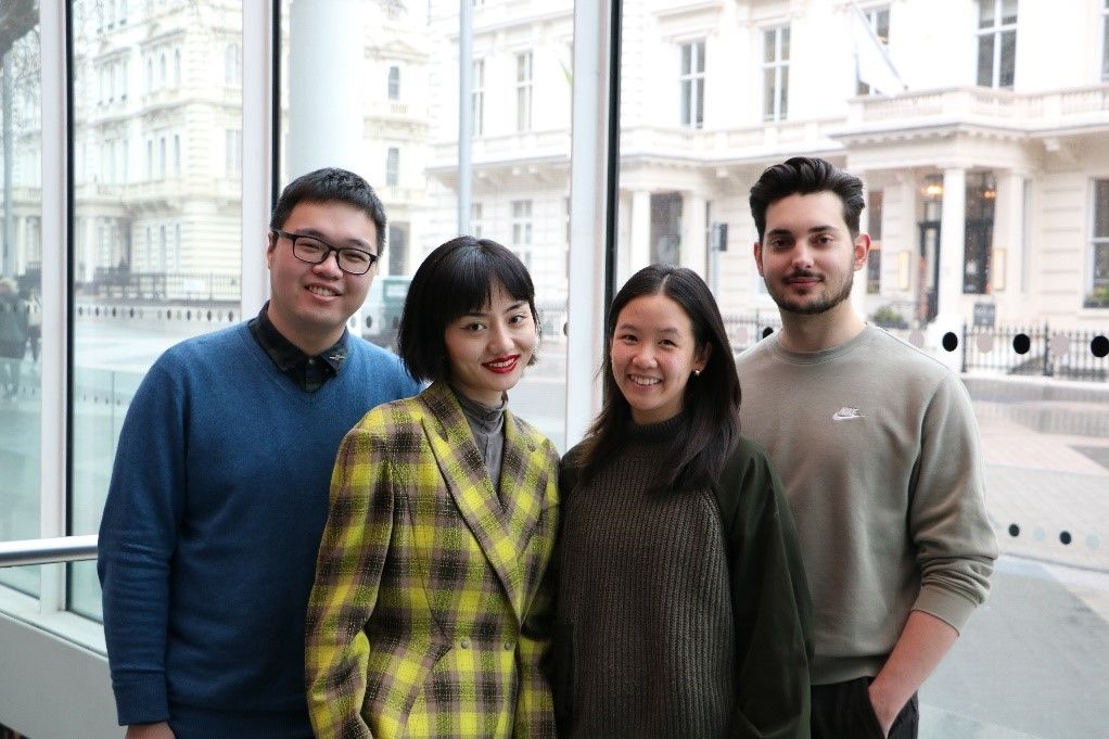 Four students, two females and two males, smiling looking at the camera