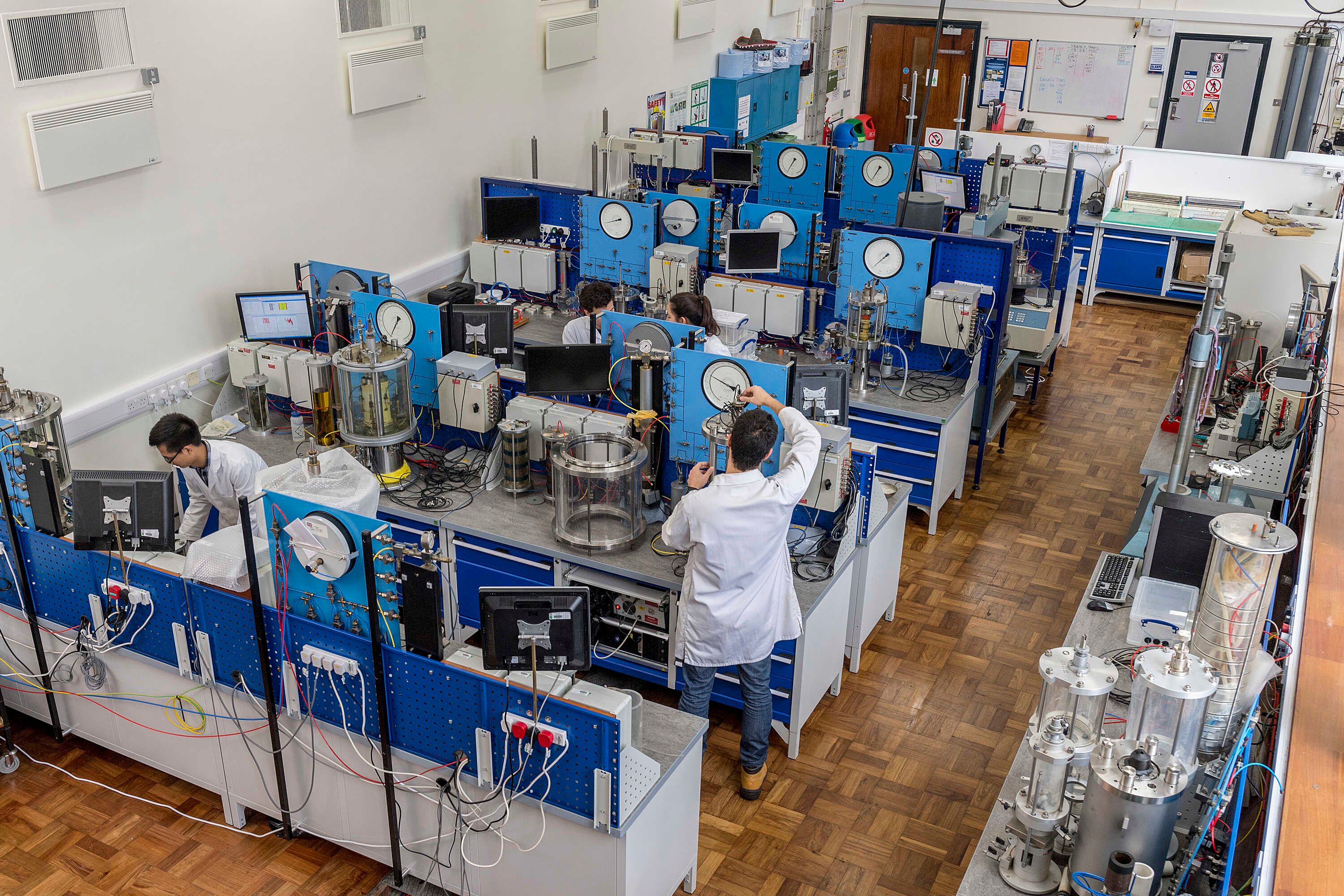 students wearing white robes working at some machines