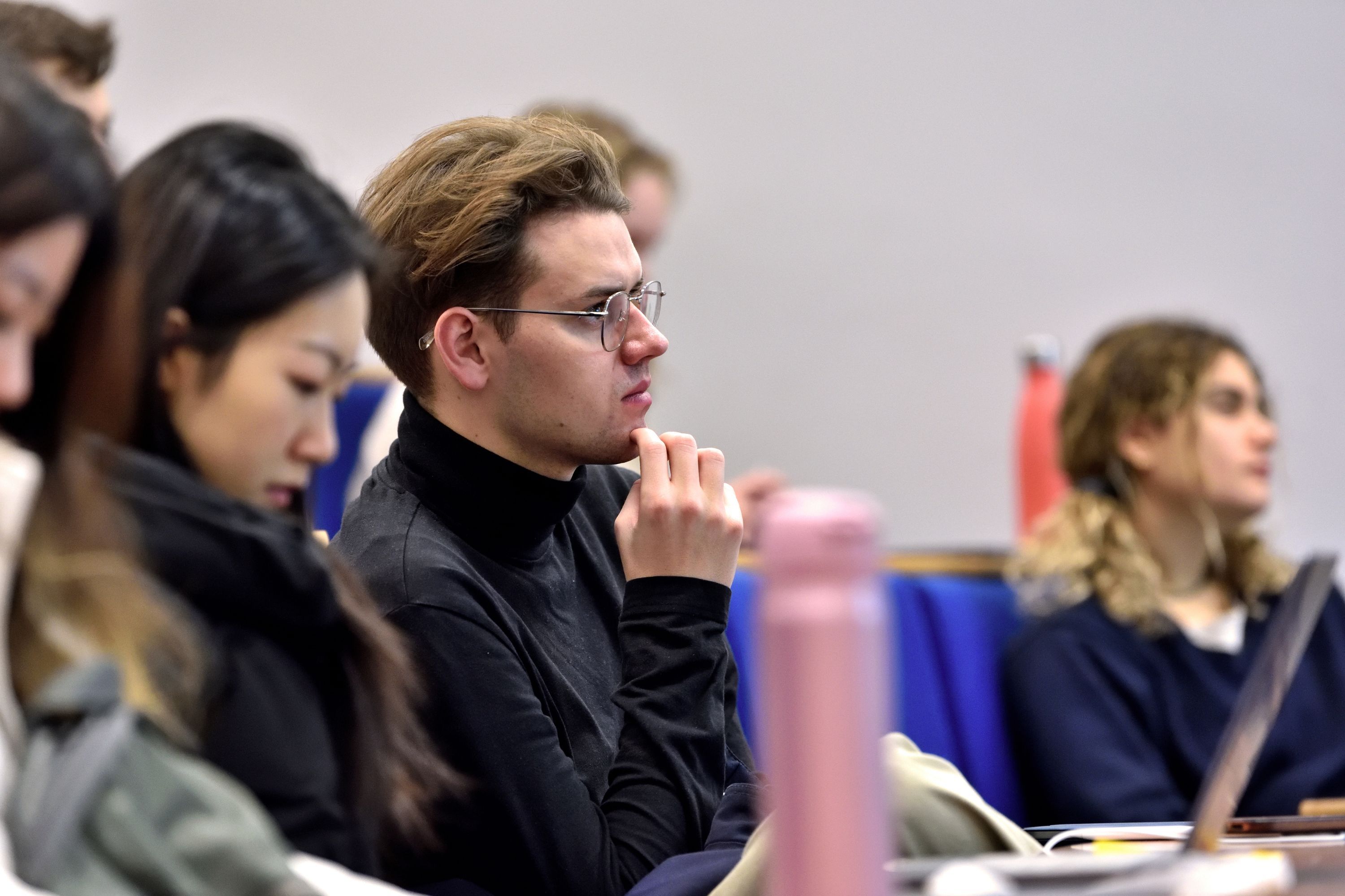 a male student in a lecture room looking straight in front of him