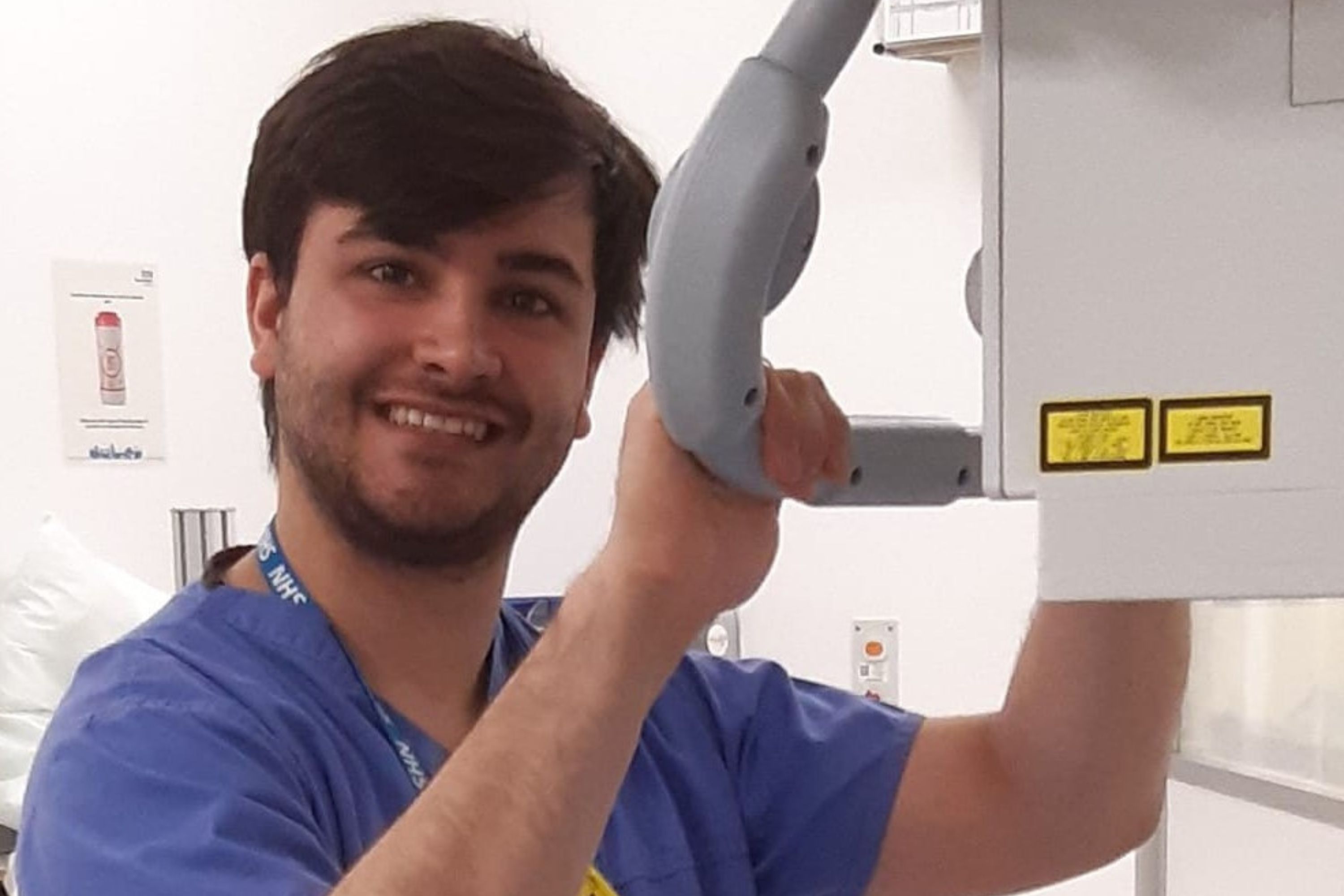 Male student handling a machinery and smiling at the camera