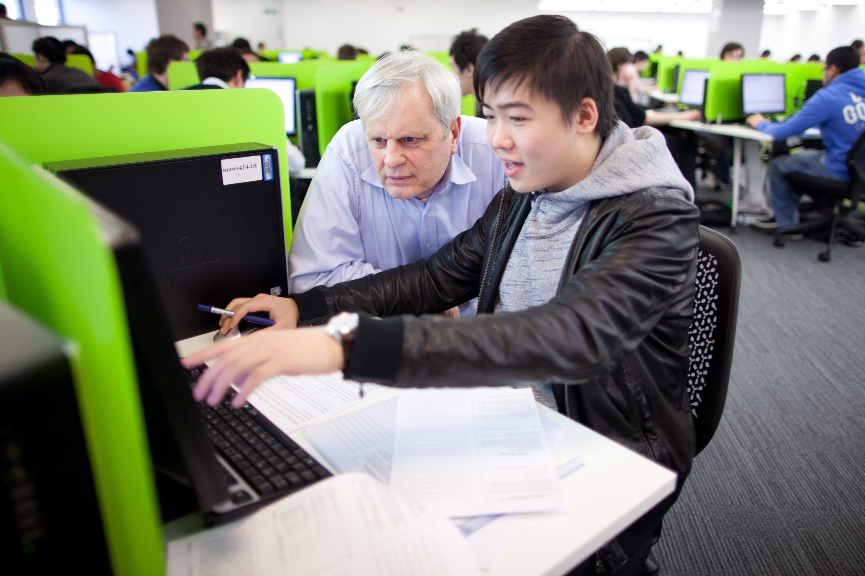 A student sat at a computer with a lecturer