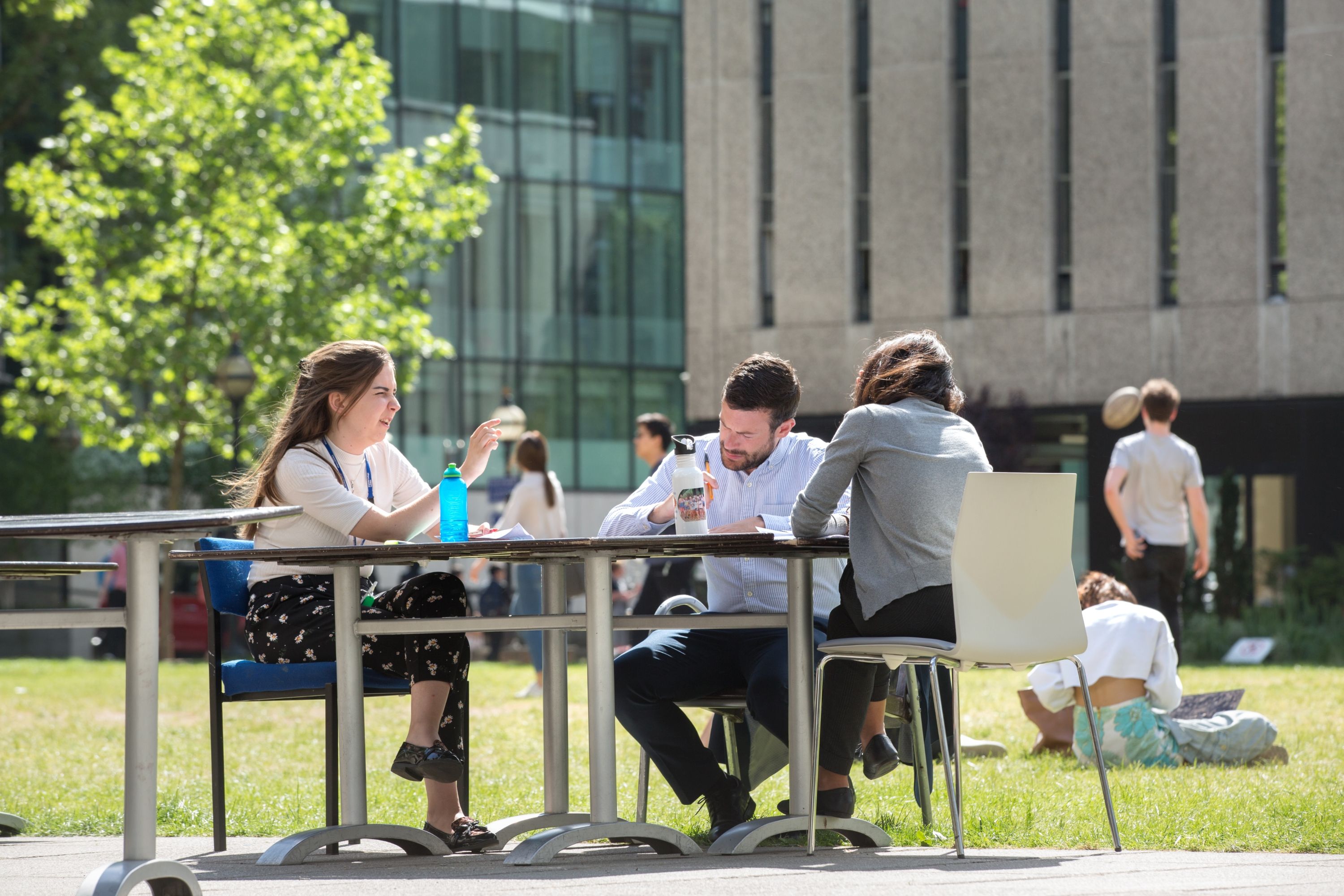 Three people sat at a table on campus