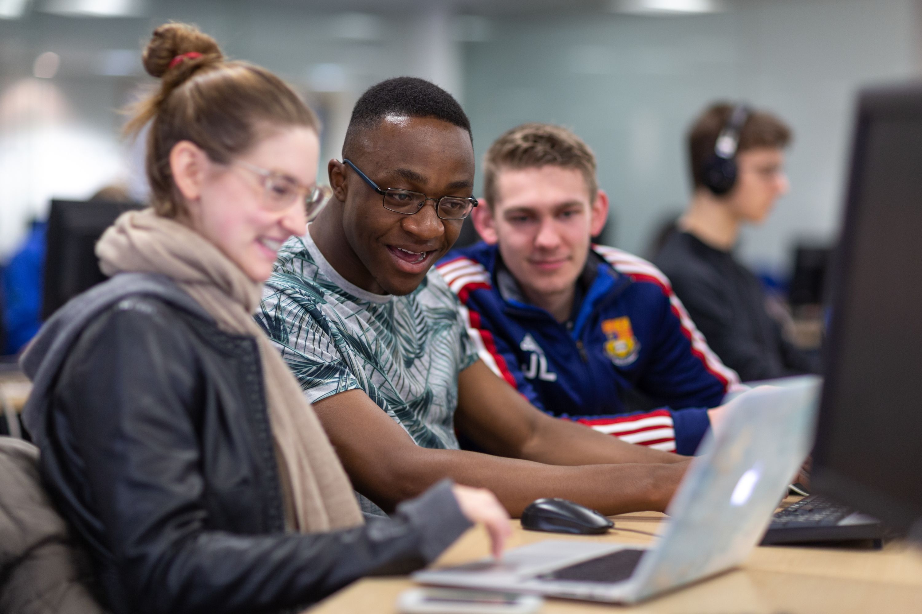 Three students looking ta a laptop