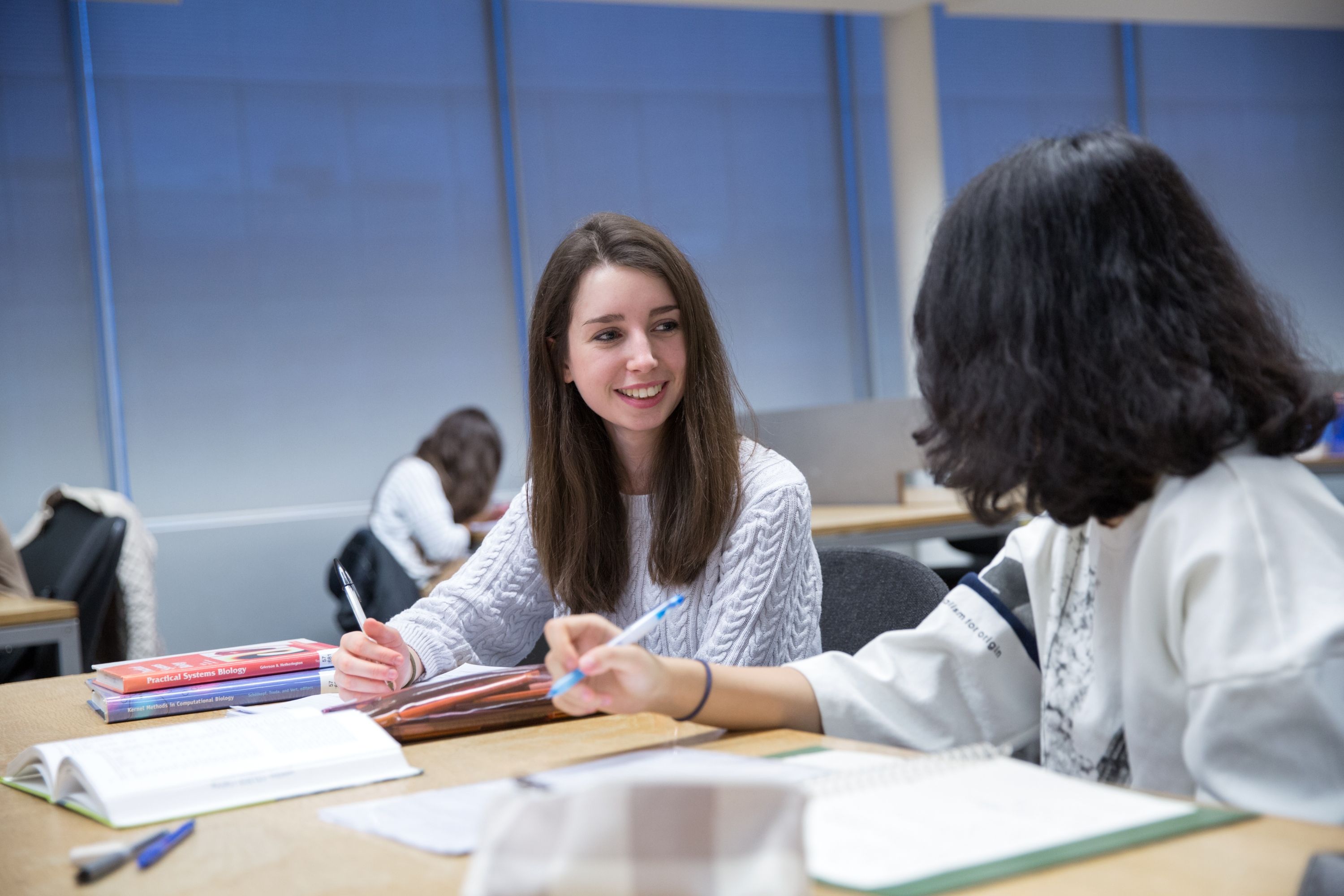 Two students smiling and writing