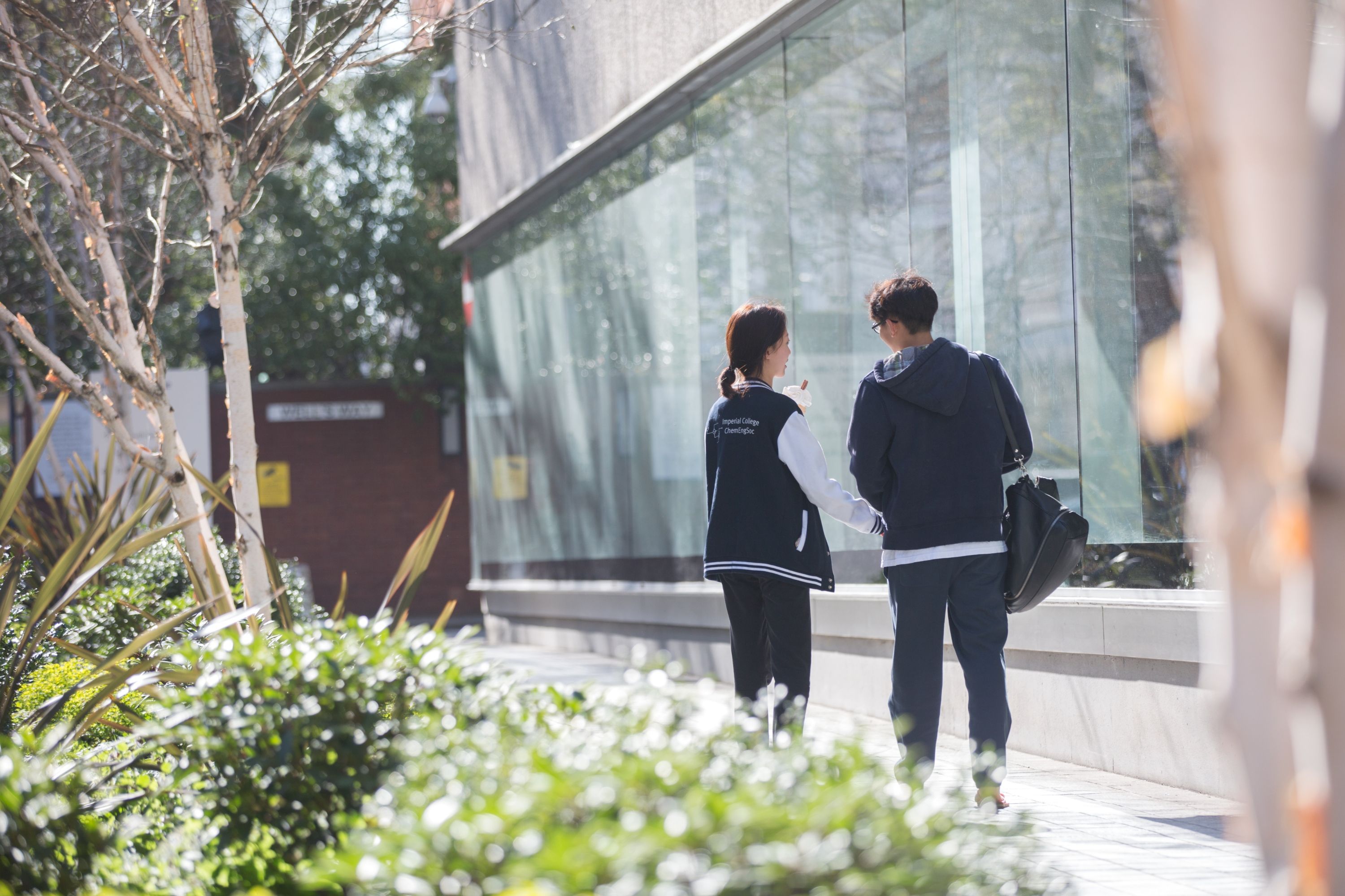 Two students walking by the library