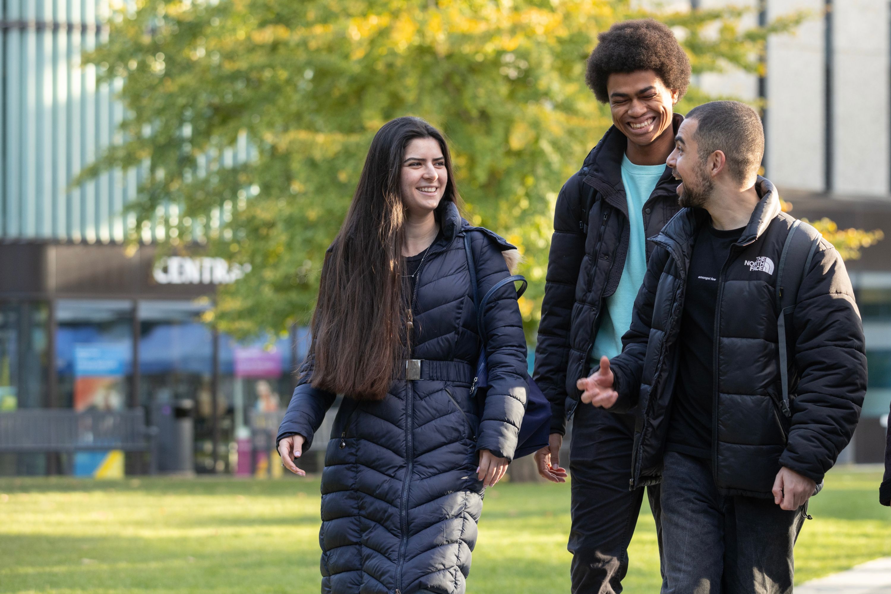 A female and two male students walk across the courtyard