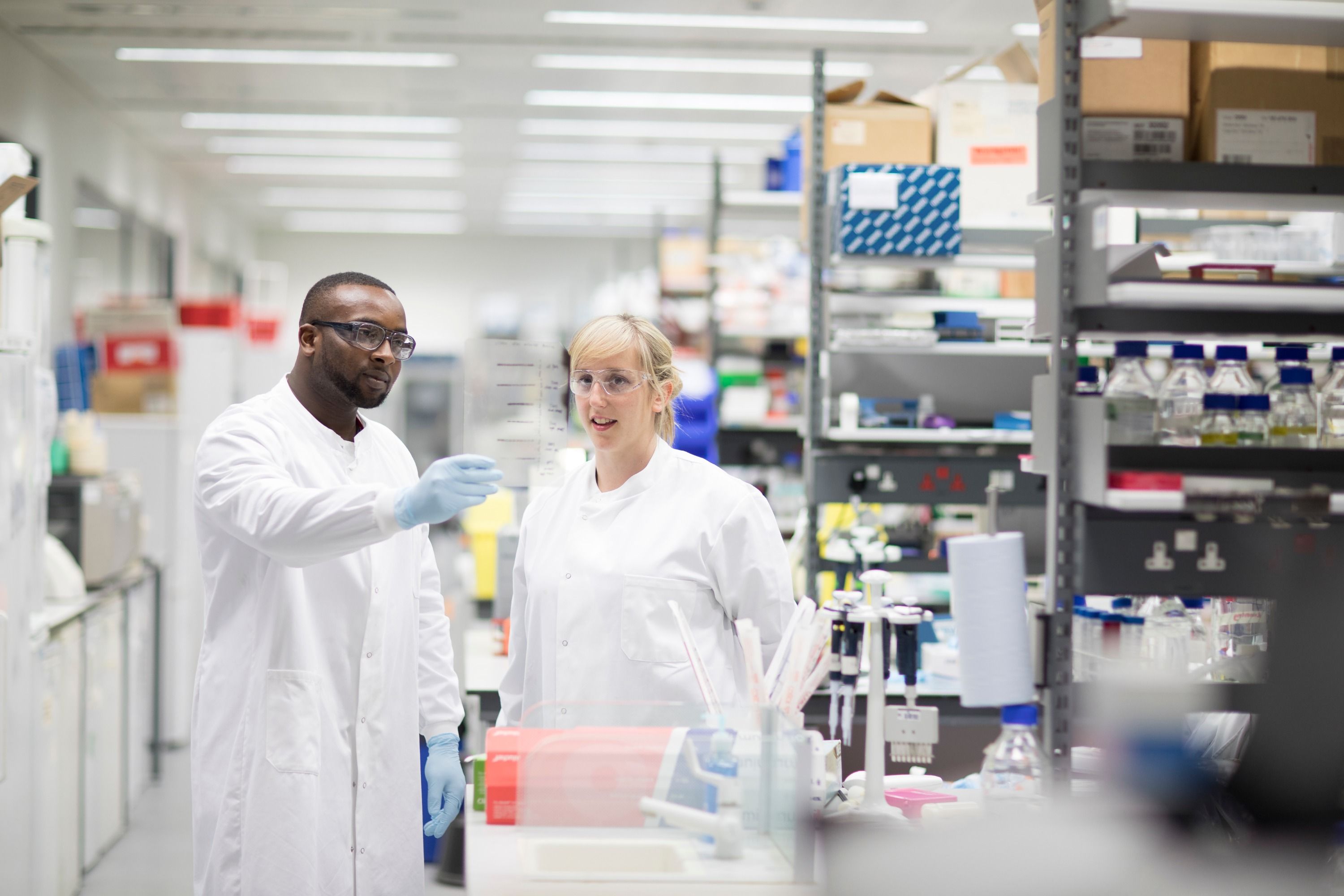 Two people in lab coats working in a lab