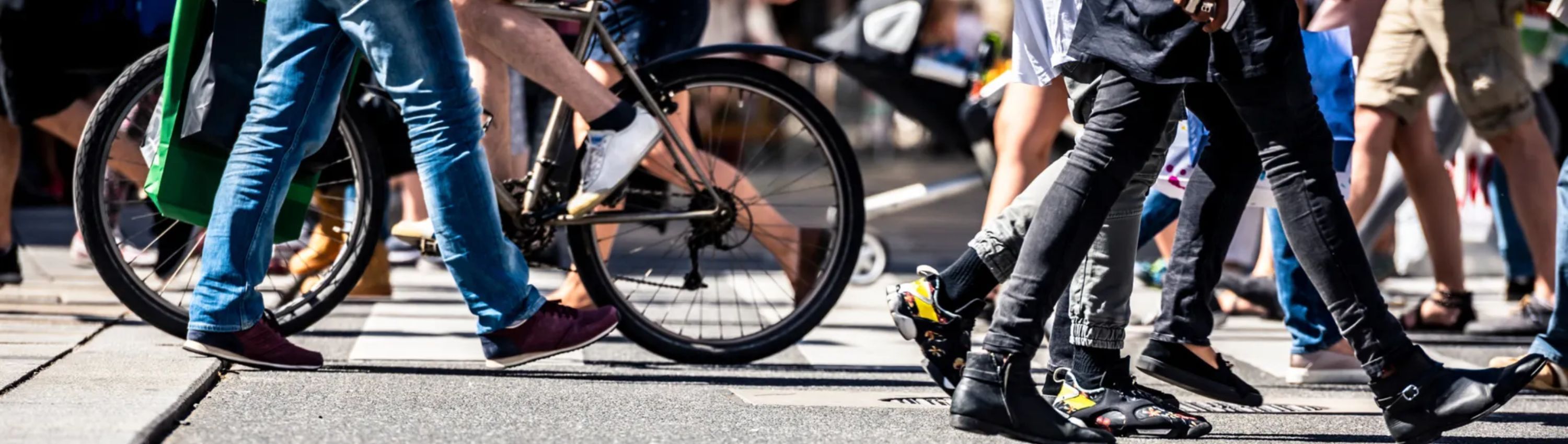 A view of people's legs as they cross a road on foot or bike