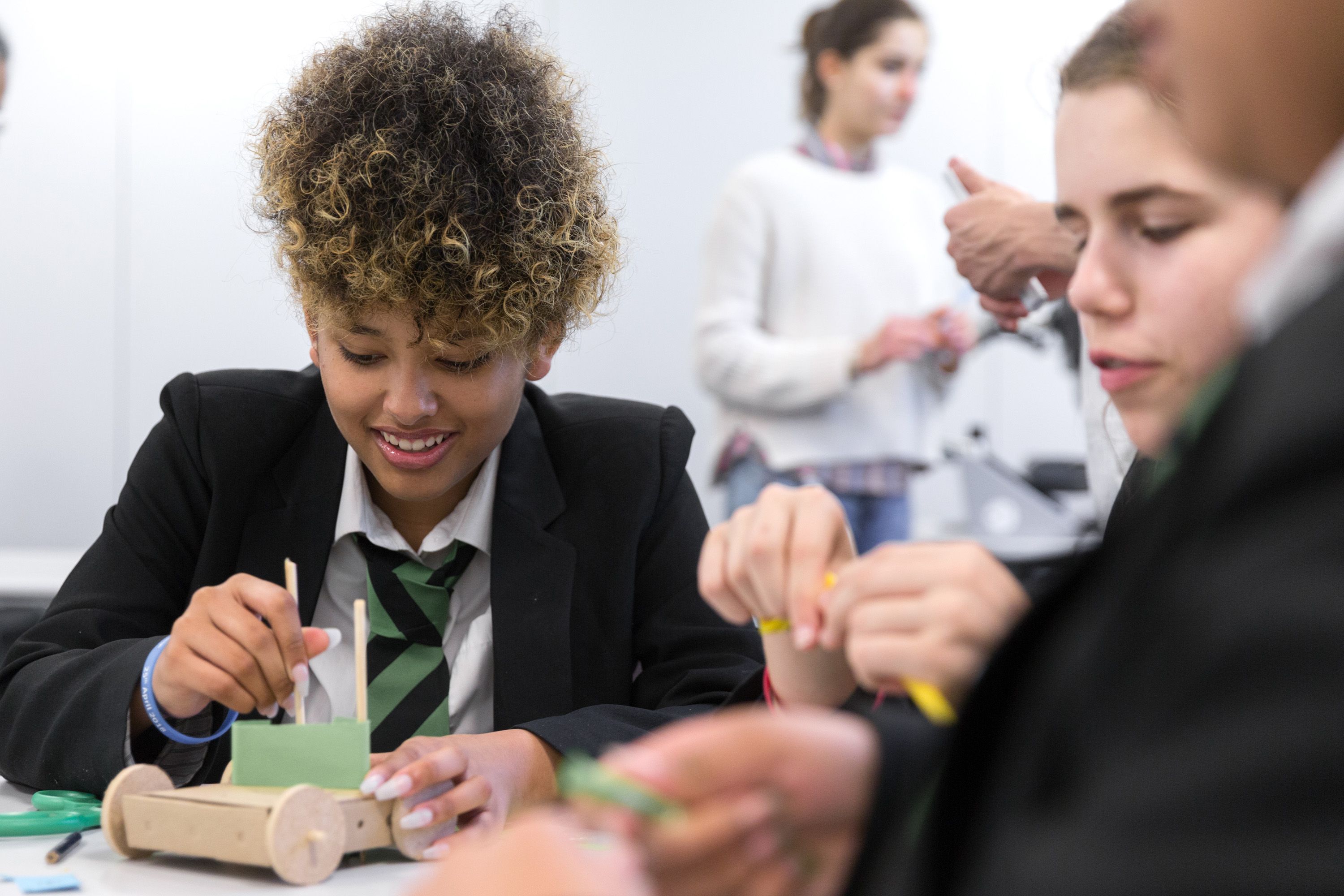 Smiling school students work at a table on a box with wheels