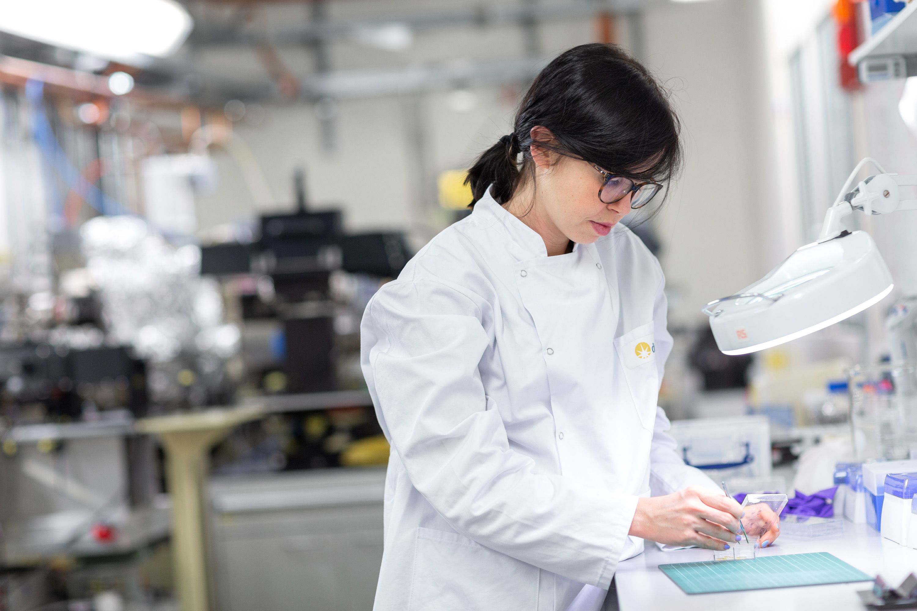 A researcher in a white lab coat working at a lab bench