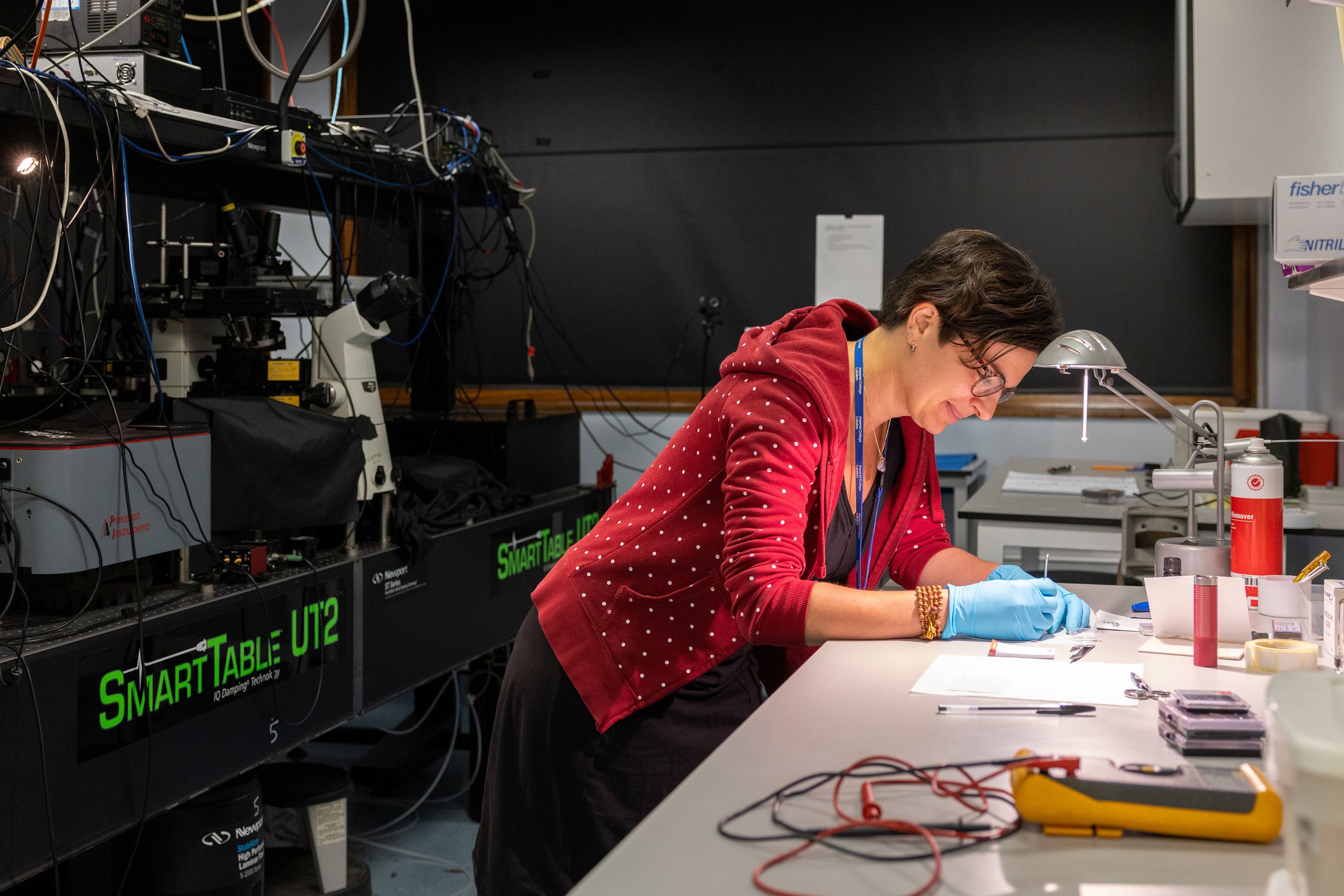 A researcher in a red hoodie works at a lab bench